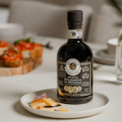Fles Mussini balsamico op tafel met kaas